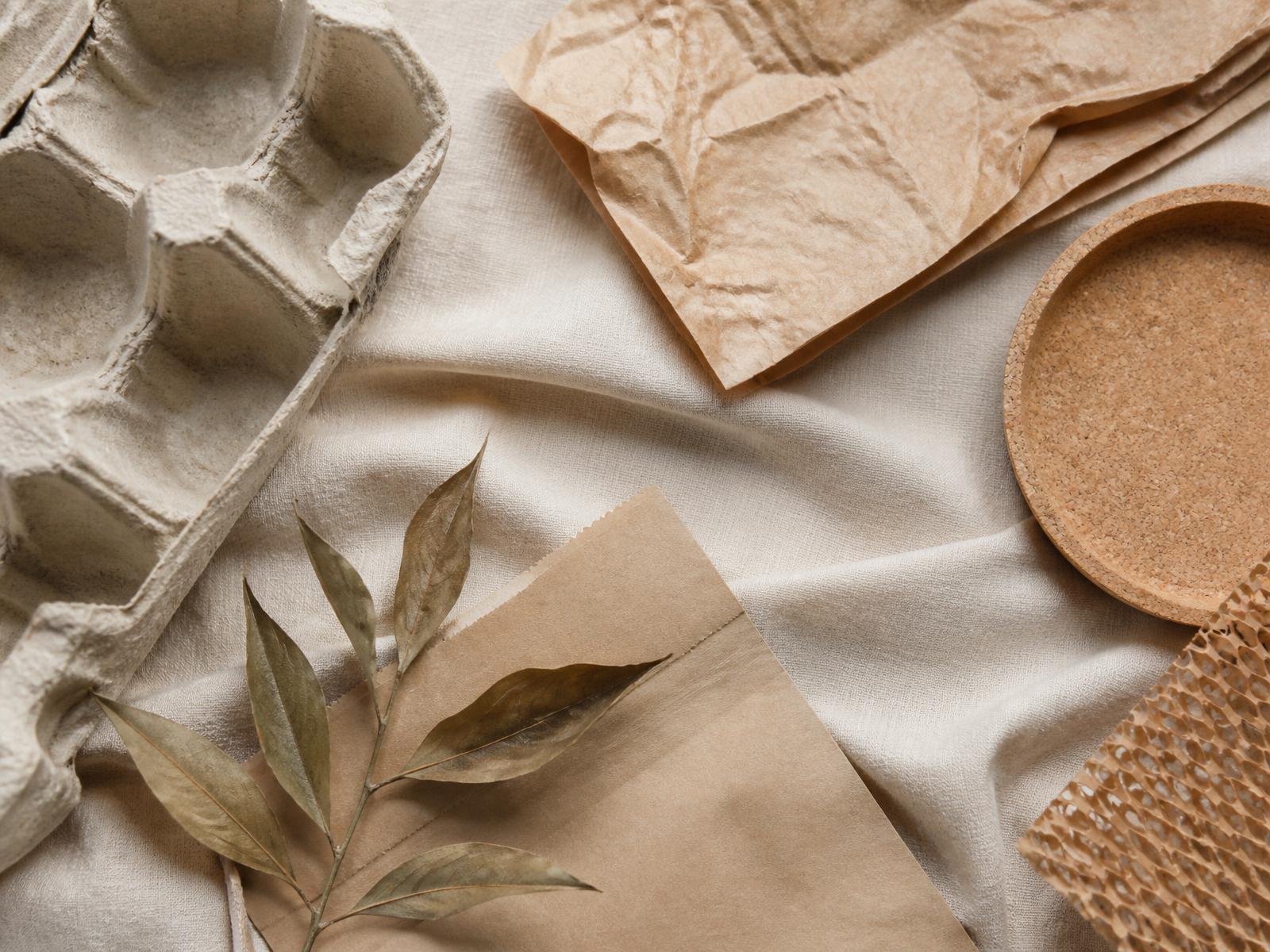 Flat lay of sustainable packaging materials, dried leaves and natural fabric